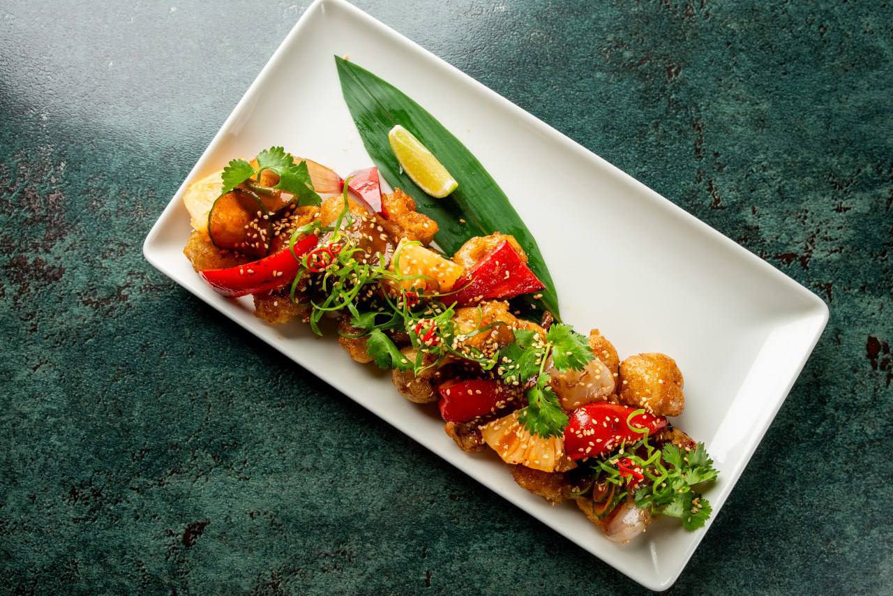 Chicken in sweet and sour sauce with peppers, pineapple, and kimchi cucumbers